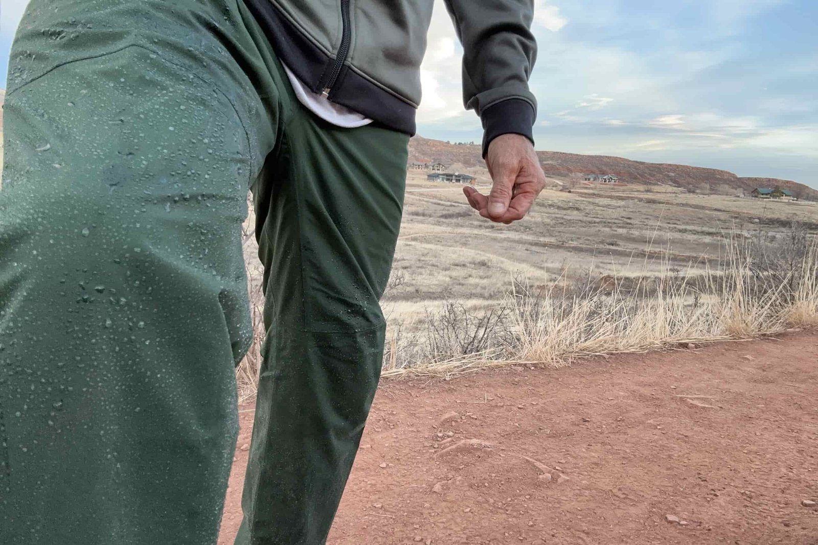 Closeup of someone wearing the green REI Trailmade rain pants.