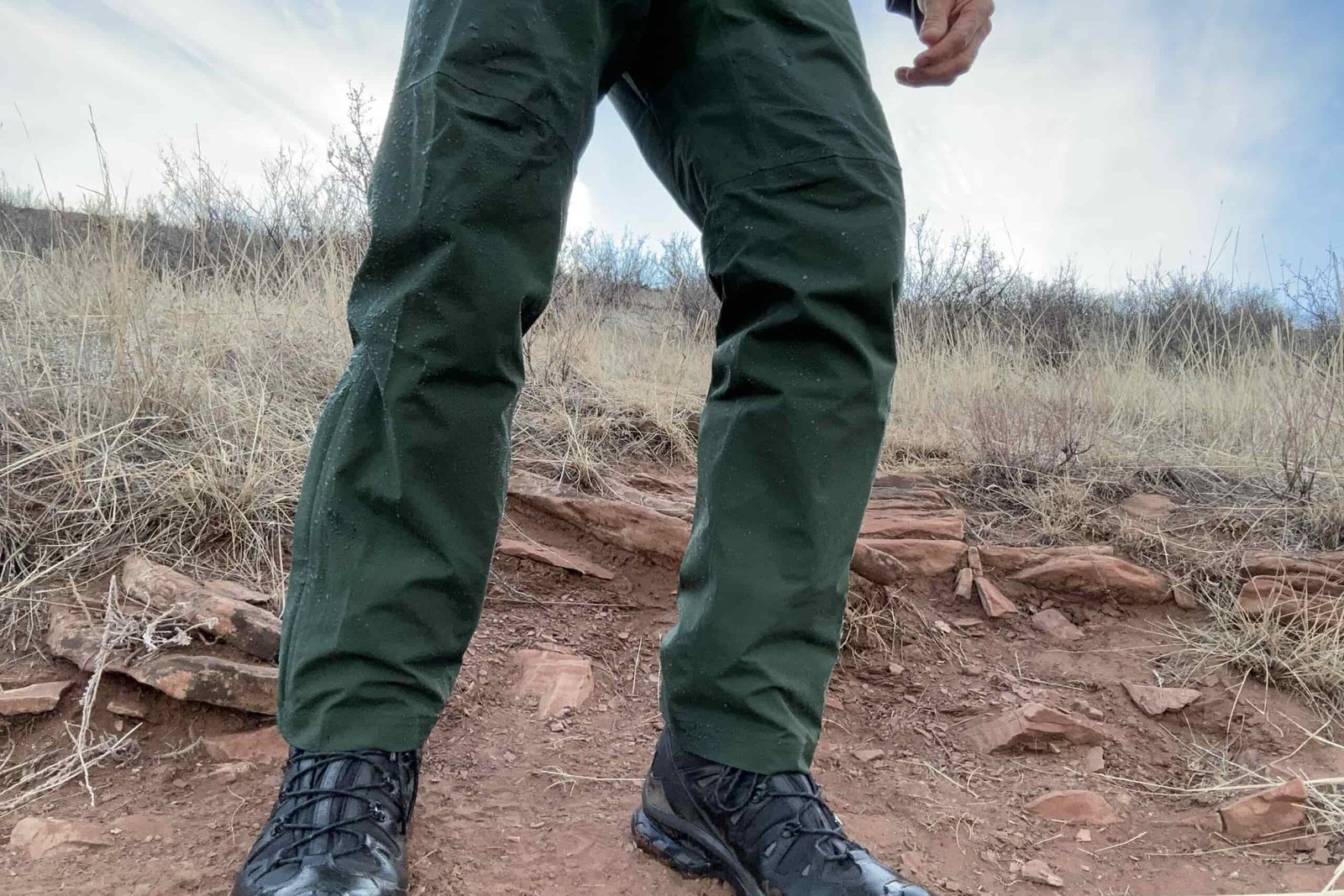 Closeup of someone wearing the green REI Trailmade rain pants.