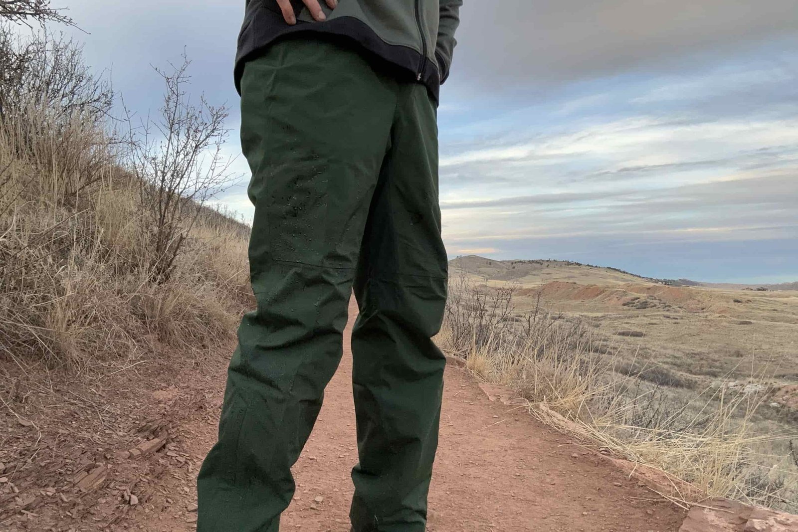Closeup of someone wearing the green REI Trailmade rain pants.