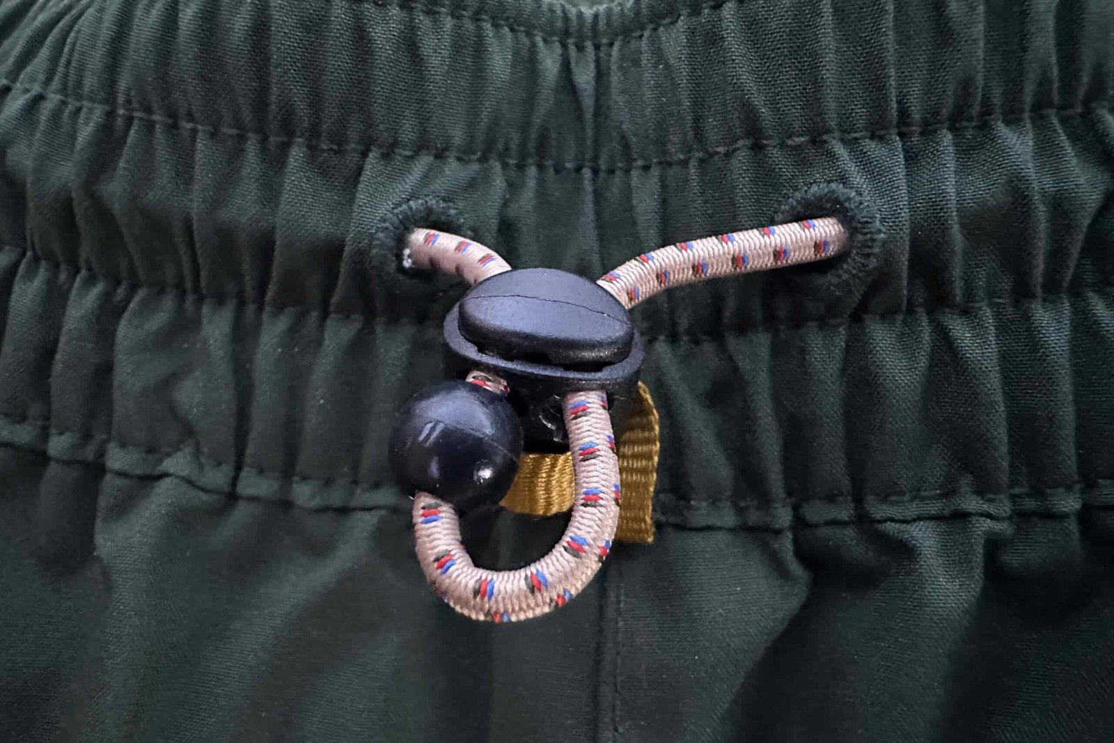 Closeup of the waistband cord of the green REI Trailmade rain pants.