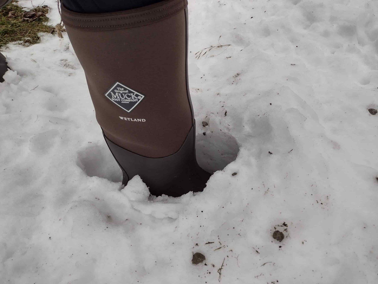 Ground level view of someone wearing the brown Original Muck Boot Wetland standing in deep snow.