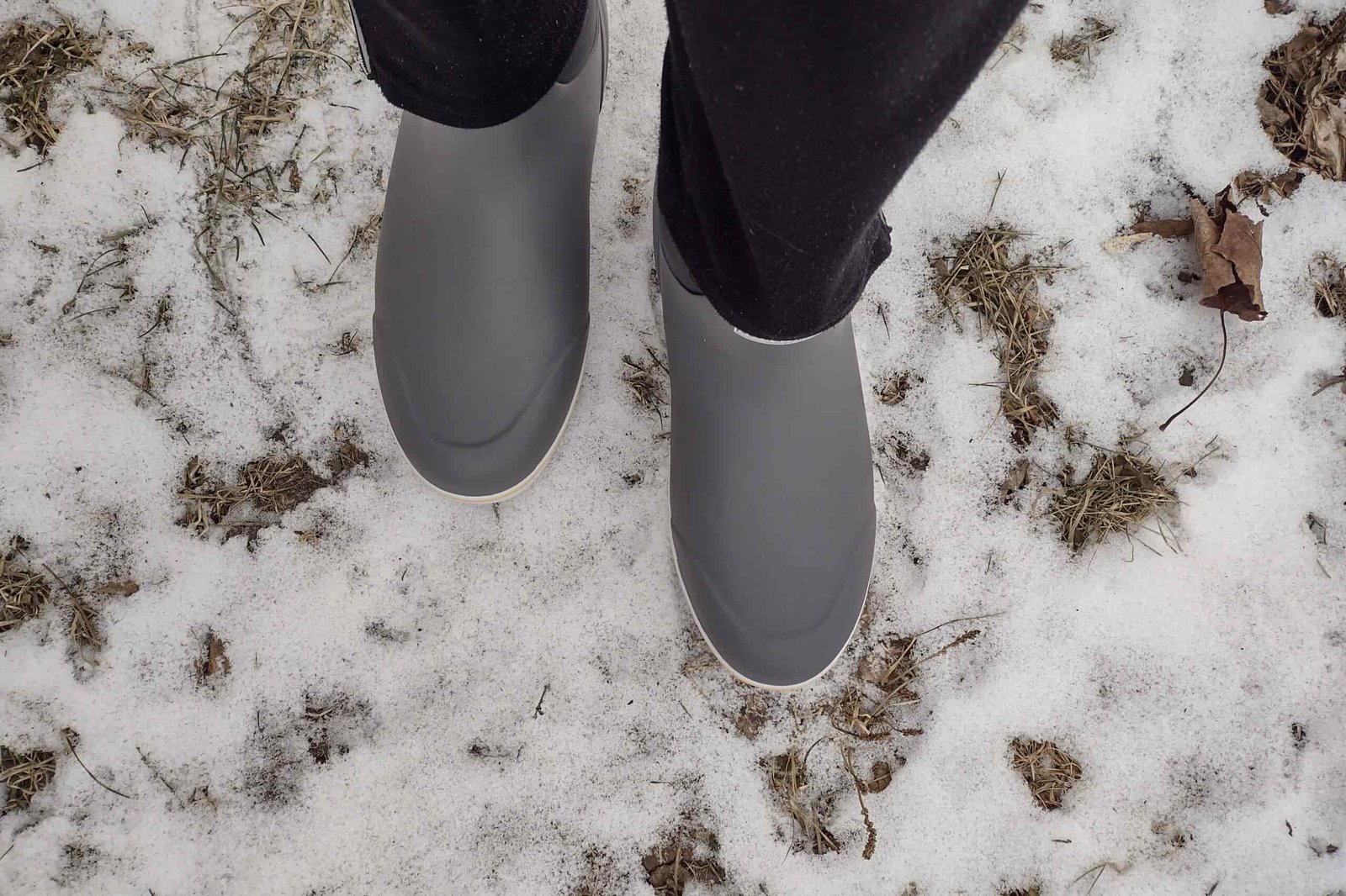 Ground level view of someone wearing the gray XTRATUF Ankle Deck Boot in light snow.