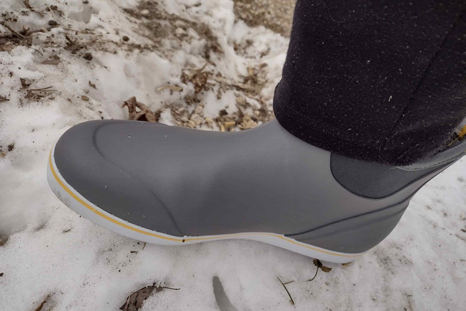 Ground level view of someone wearing the gray XTRATUF Ankle Deck Boot on snow.
