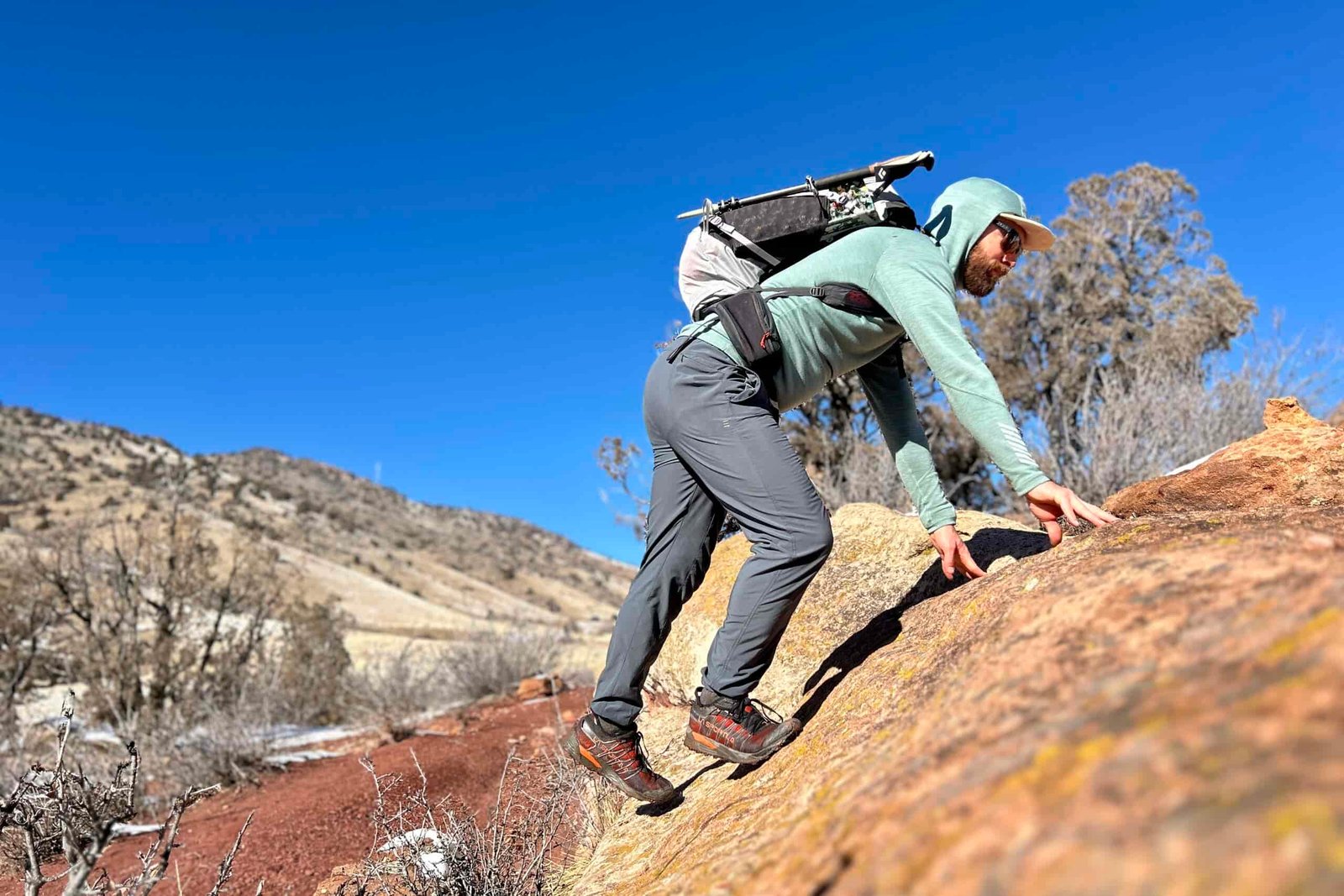 A man scrambles up a rock on a technical hike.