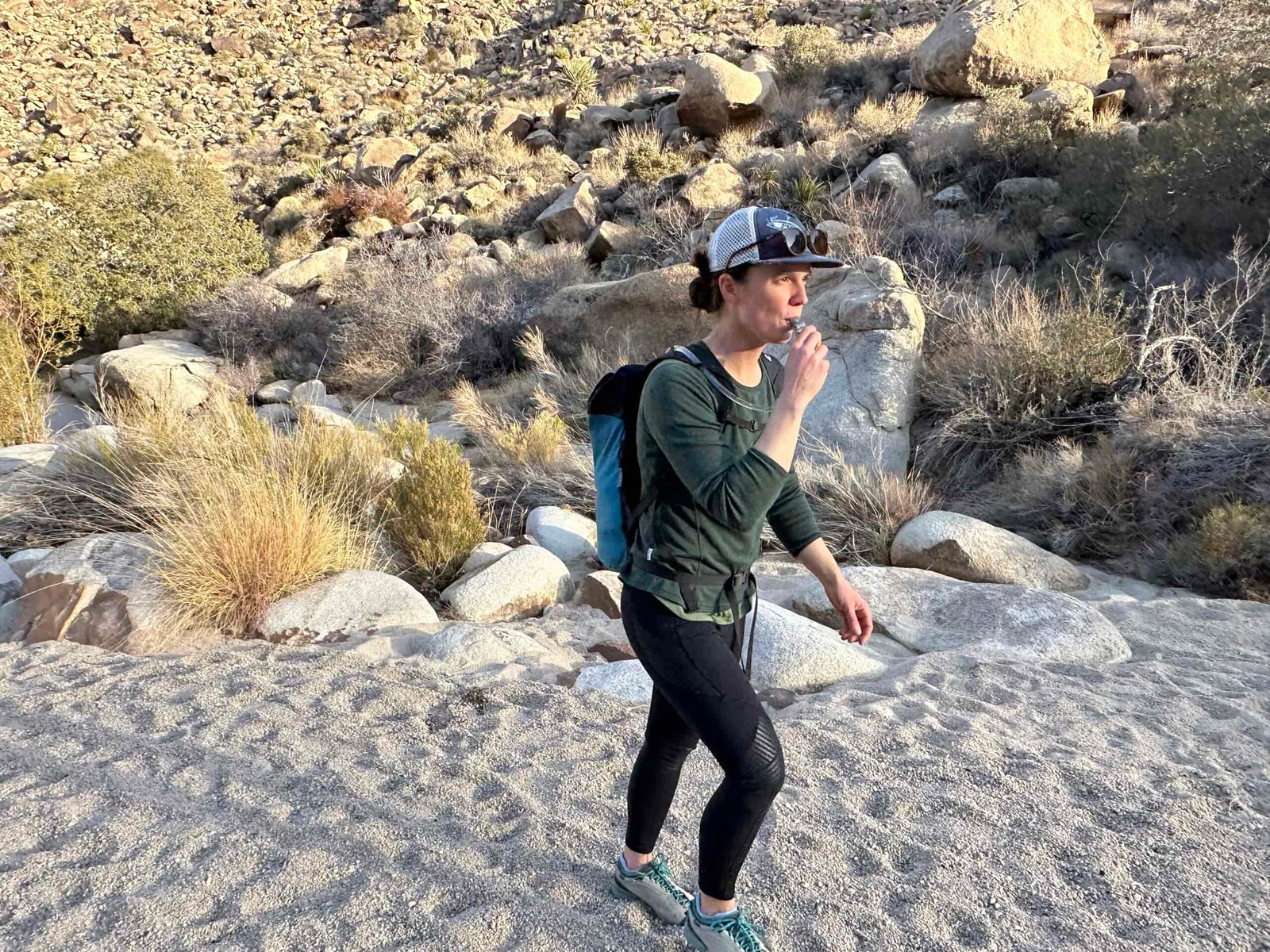 A hiker walks through Rattlesnake Canyon in Joshua Tree National Park while drinking from a hydration bladder.