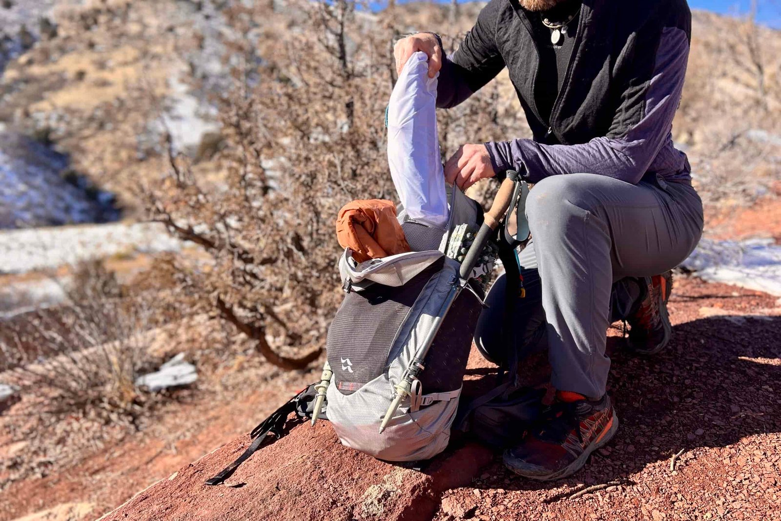 A person puts a small backpacking chair into a backpack for carrying.