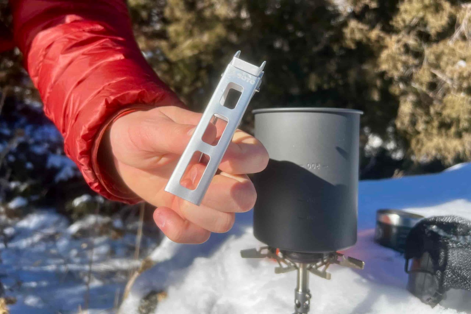 A hand shows the pot lifter of the thermostack combo with the aluminum pot in the background.