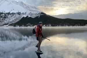 A man ice skates wearing a red jacket.
