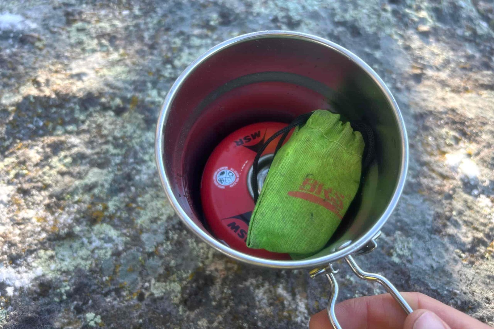 a backpacking stove and fuel canister stored inside a stanley adventure cookpot