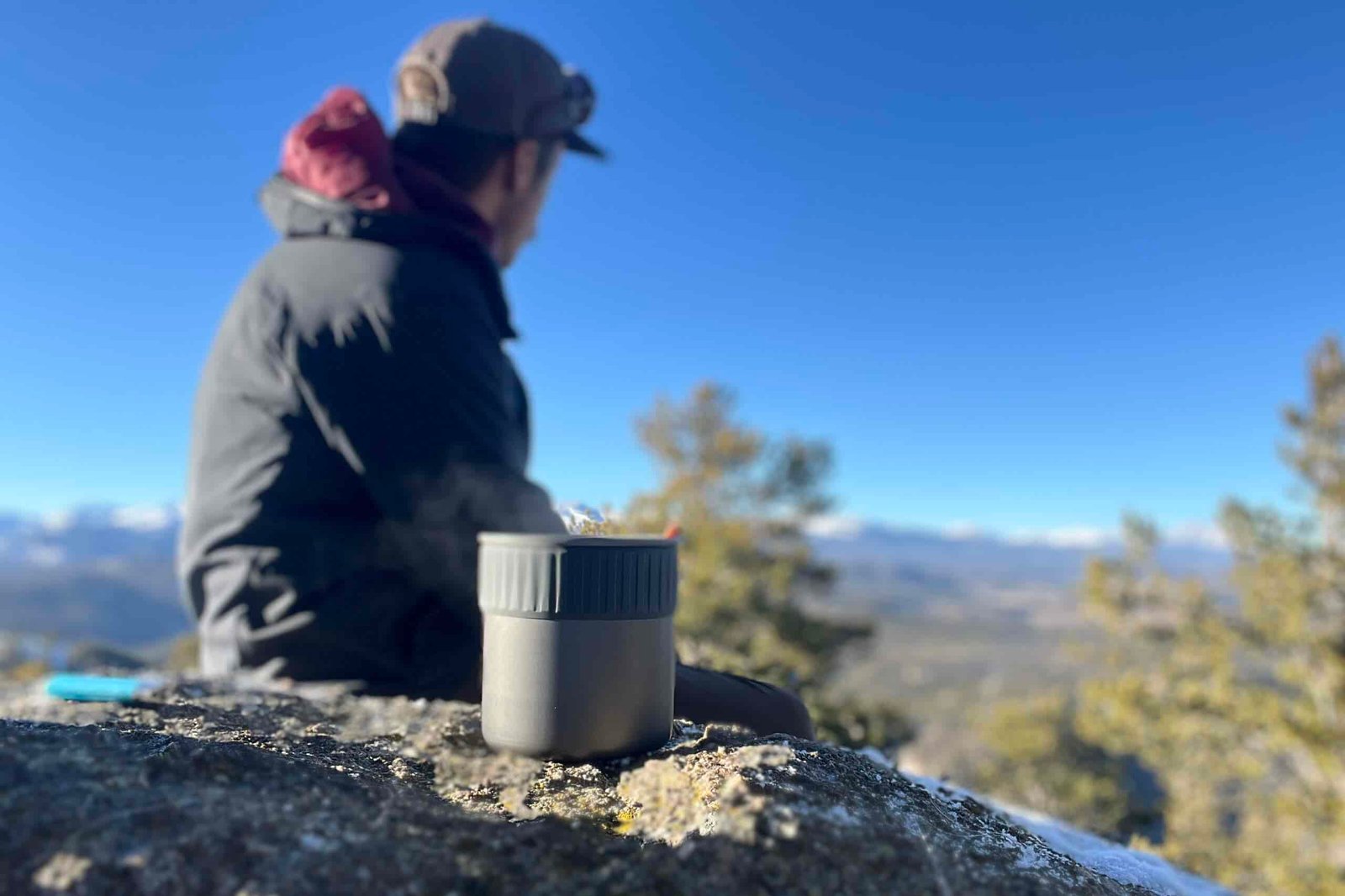 A hiker looks out over a mountain view with the trail mini solo in the foreground.