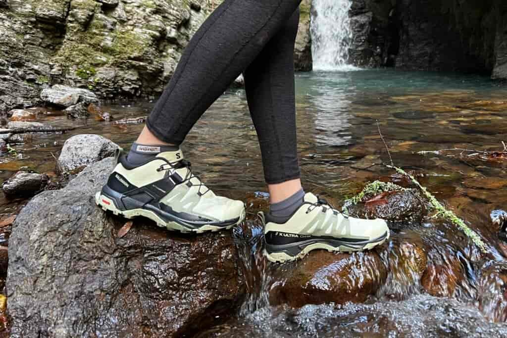 Women walking a cross a creek, with a waterfall in the background.