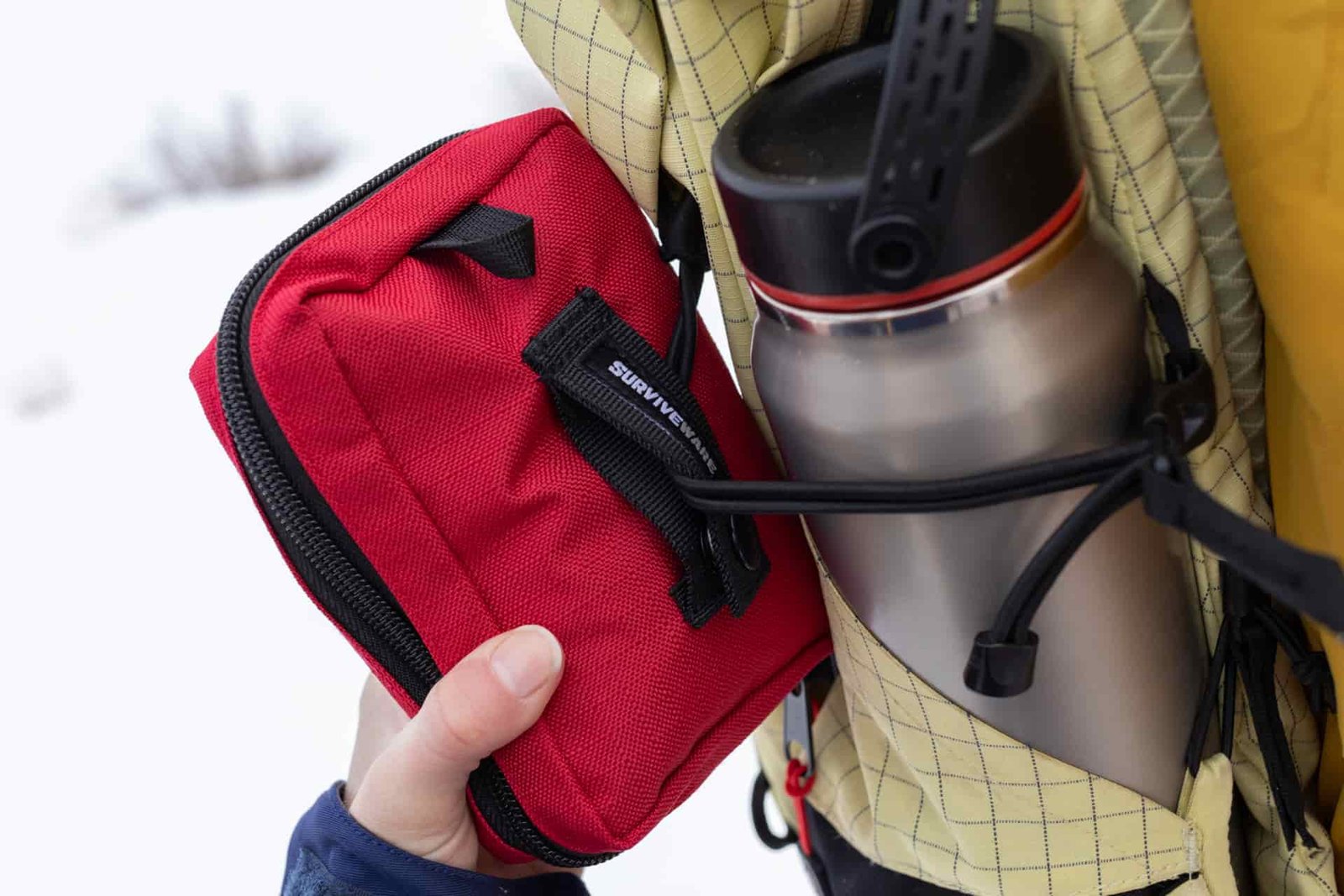The Surviveware Small looped onto an exterior pack strap.