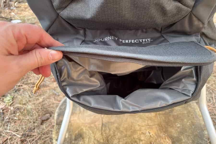 A detailed shot of the Kelty Journey PerfectFIT Signature logo on the bottom storage compartment of the baby carrier, emphasizing branding and design.