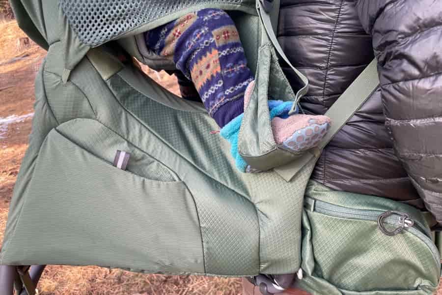 A side view of the Osprey Poco Premium, highlighting the child’s foot stirrup and storage pockets.