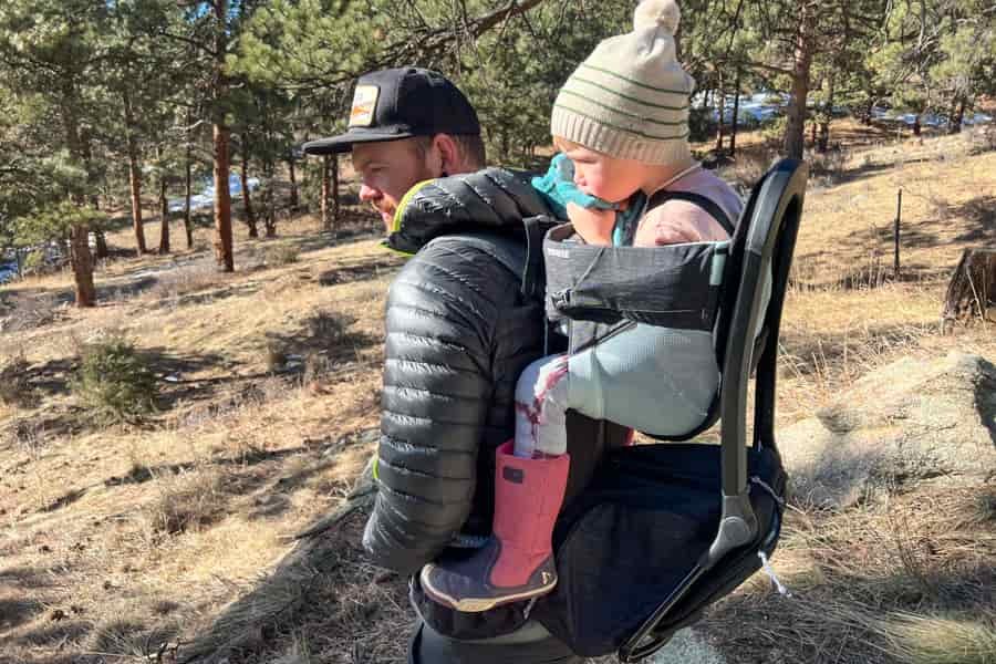 A caregiver hiking with the Thule Sapling, showcasing the comfortable fit and ergonomic design for both wearer and child.