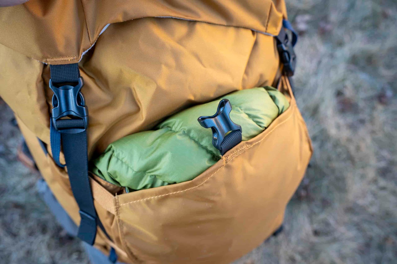 front pocket of backpack stuffed with green jacket
