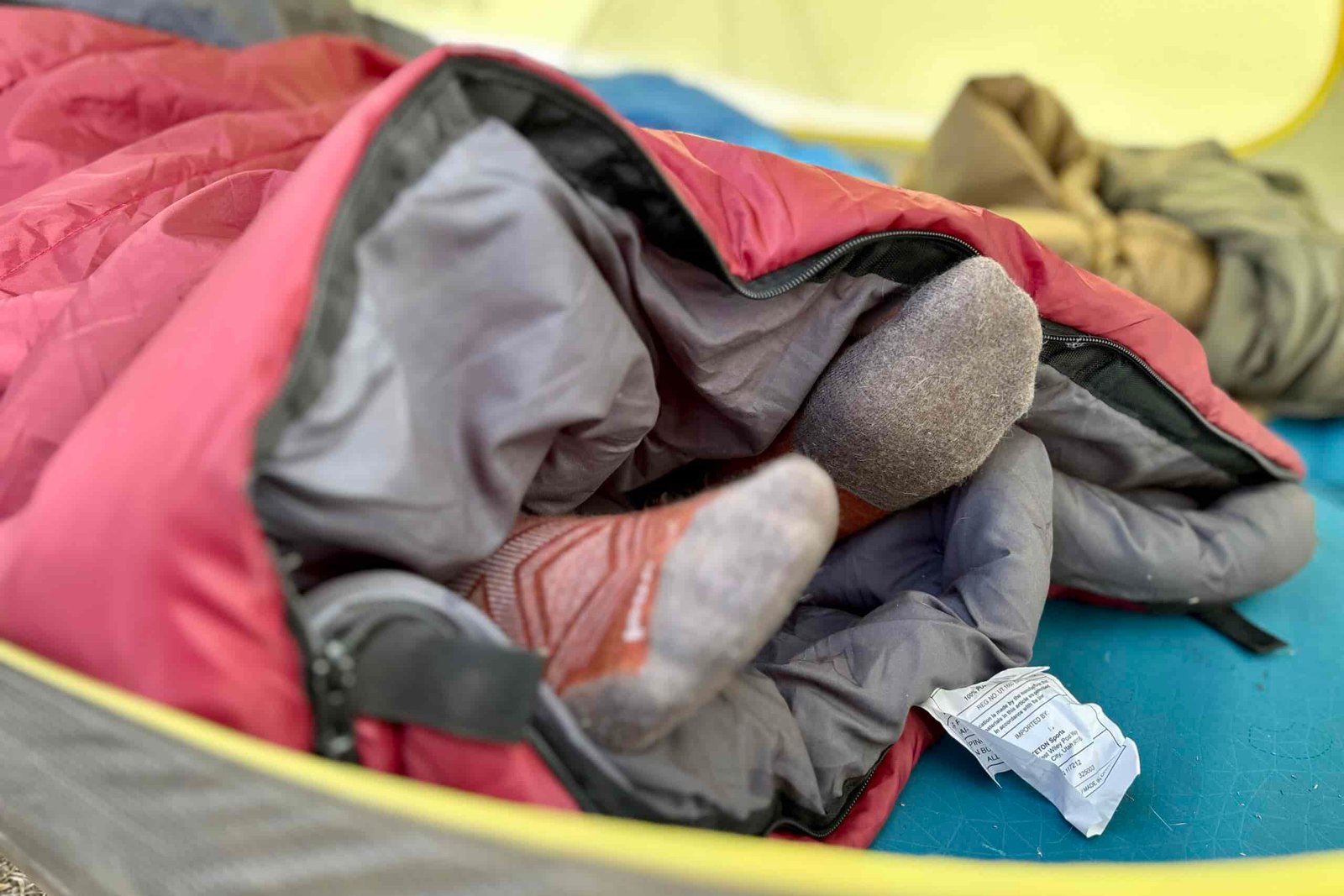 Close-up image of two feet sticking out of the unzipped bottom of a sleeping bag.