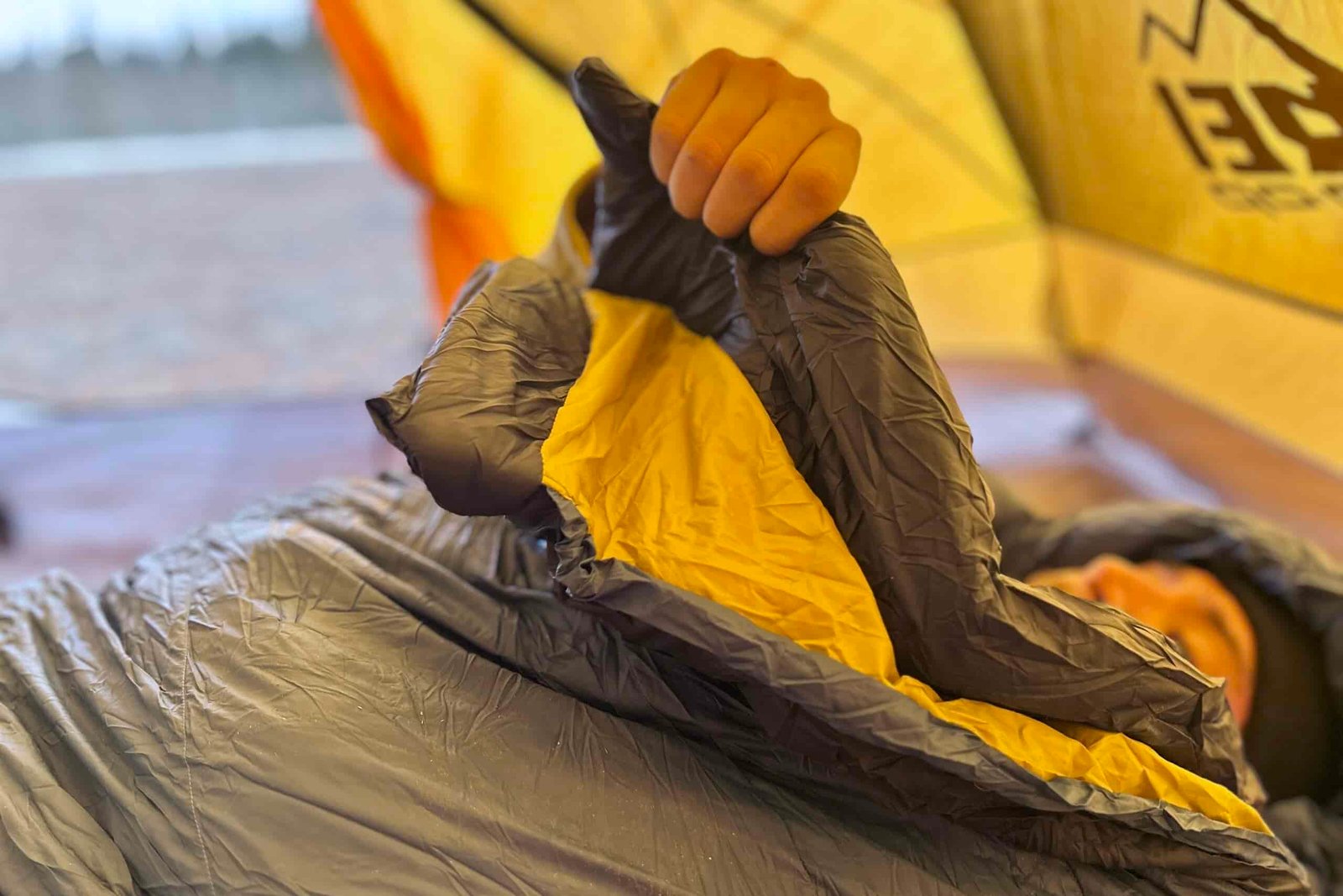 Close-up shot of a person grasping the draft tubes of a sleeping bag.