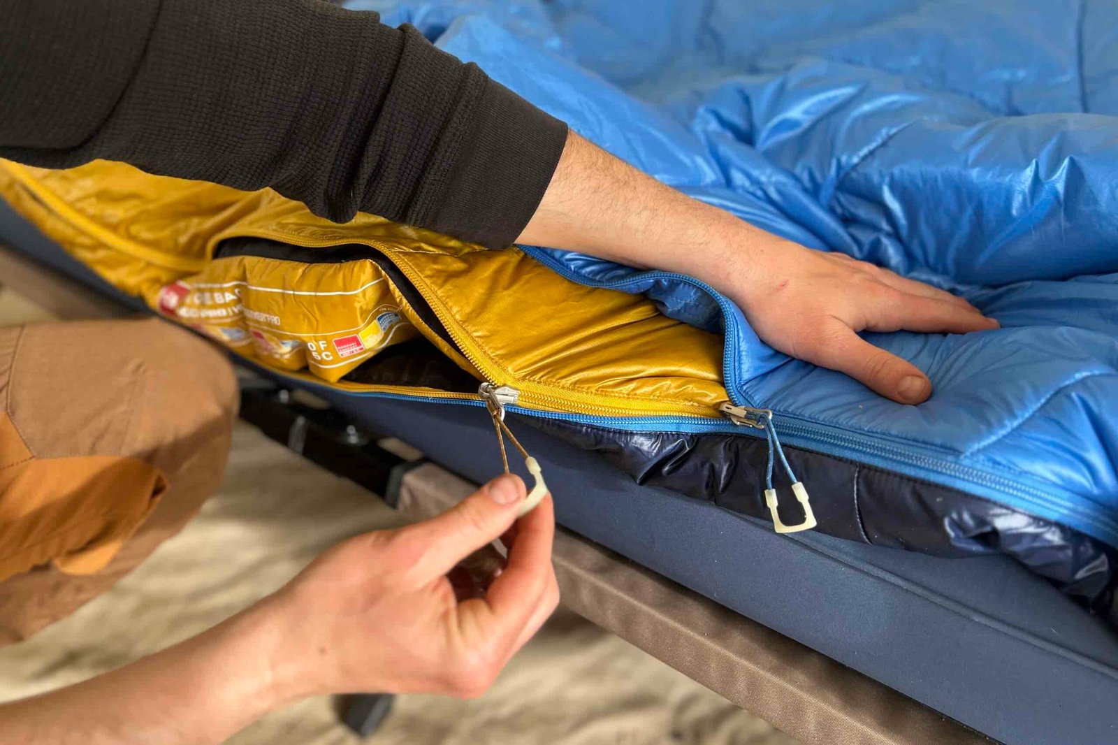 Close-up image of a person zipping up the inside of a two-layer sleeping bag.