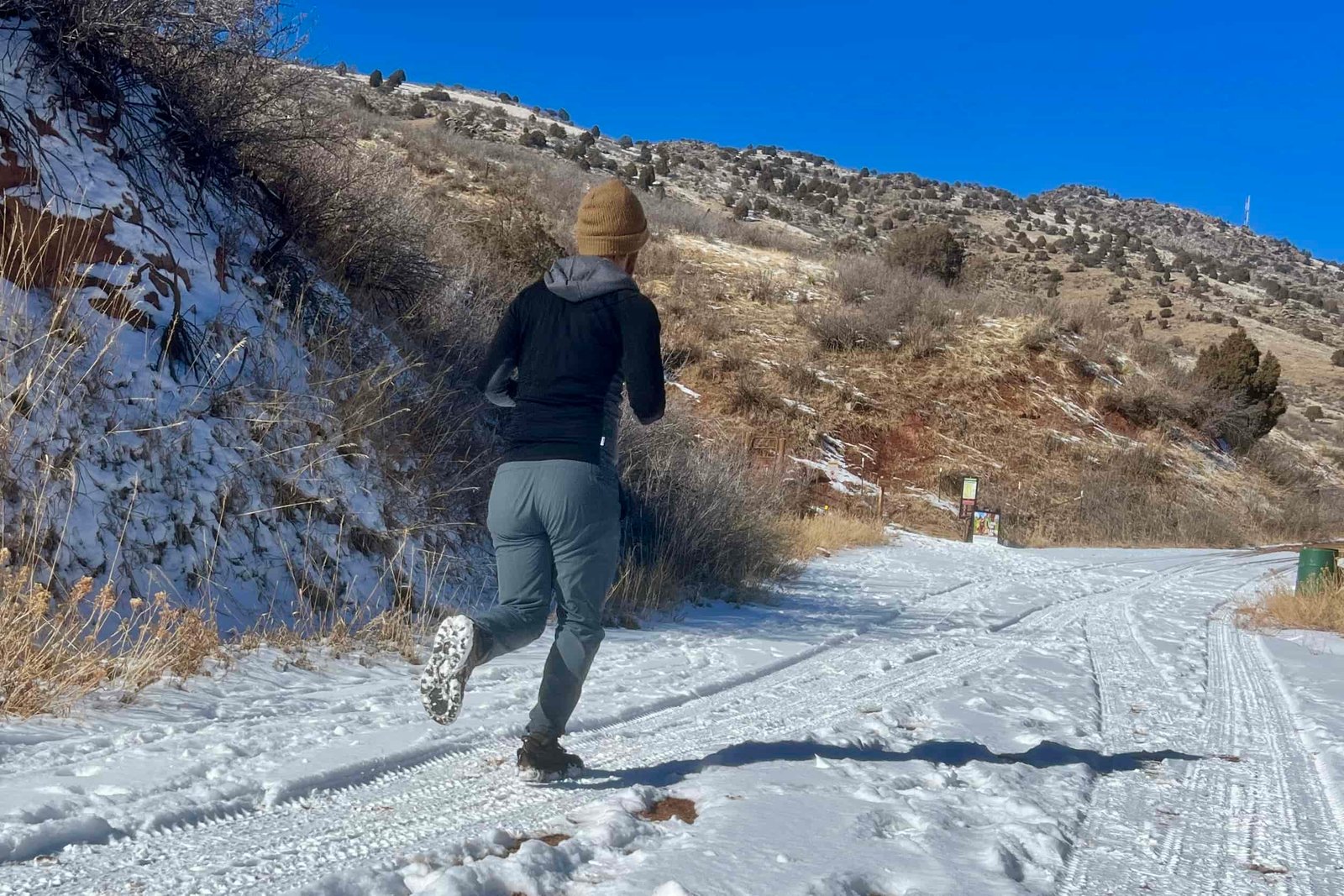 A hiker runs on snowy ground with a pair of ice cleats on a desert background.