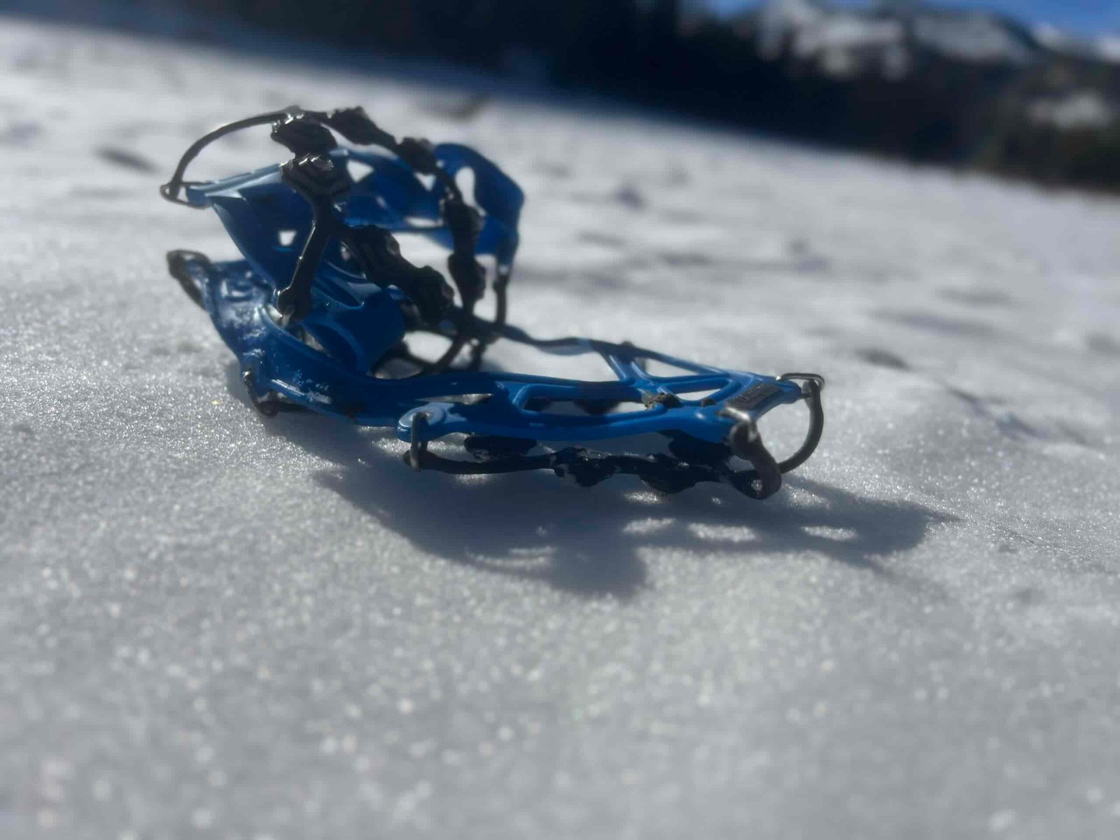 A pair of ice cleats sit on the snowy ground.
