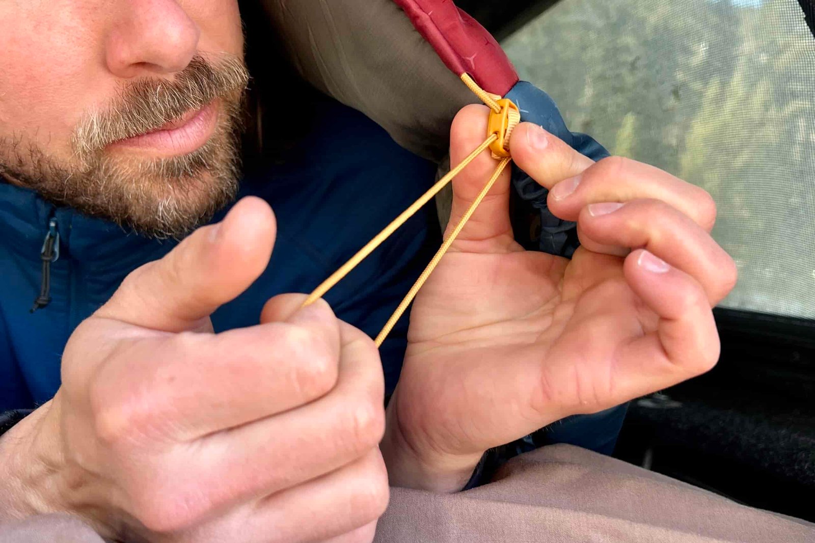 Close up of a man cinching the collar of a sleeping bag.