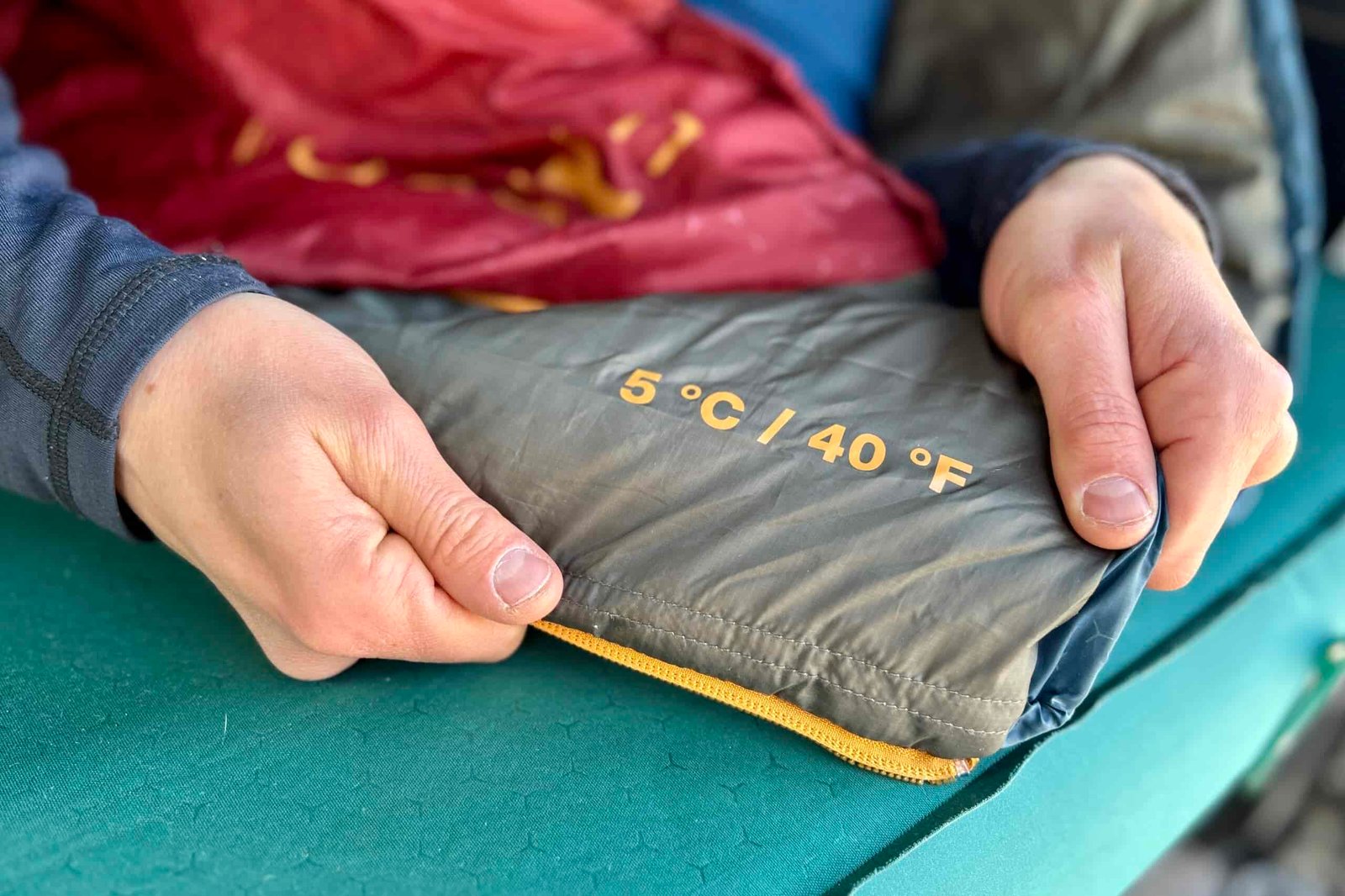 Two hands displaying the printed temperature rating on a sleeping bag.