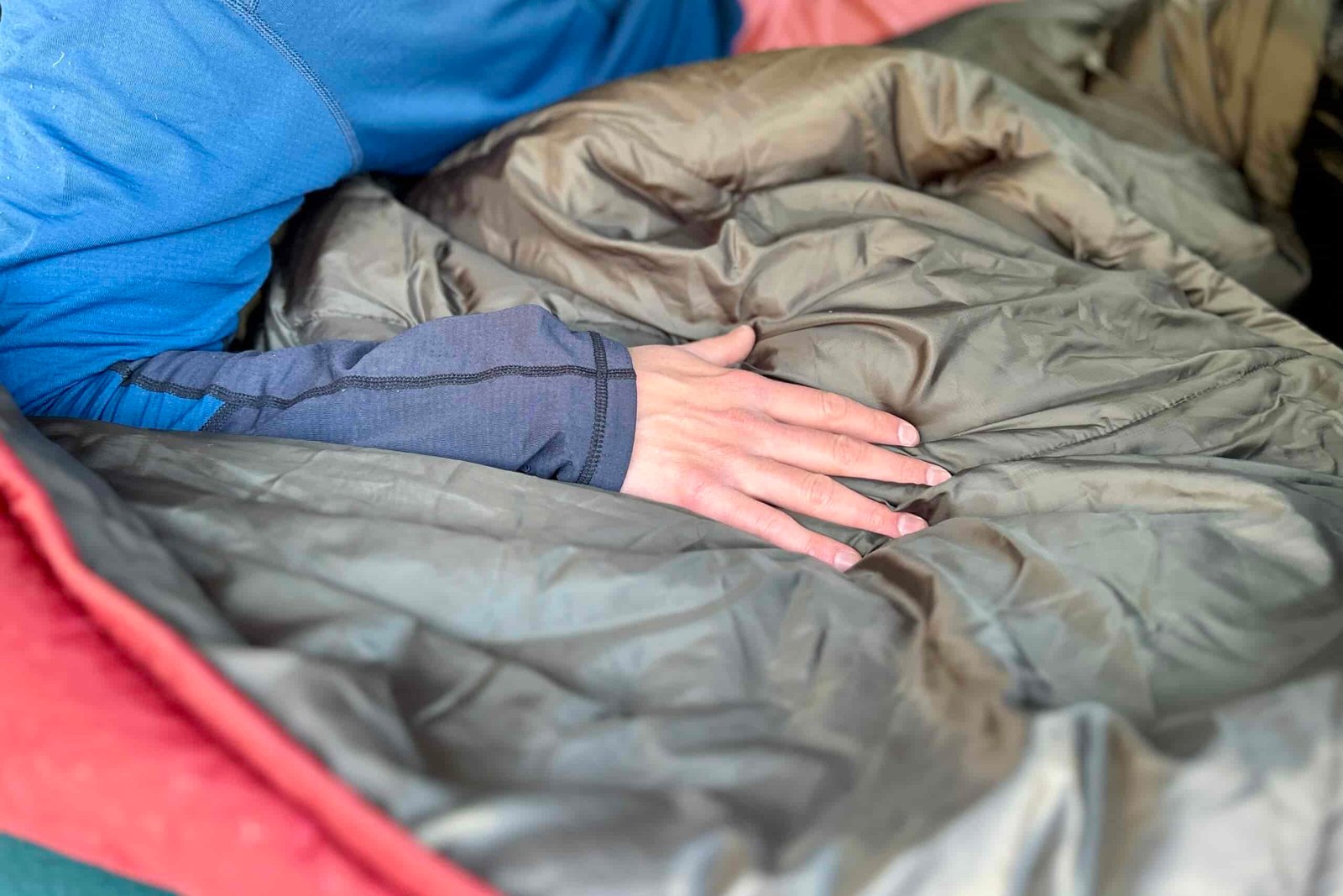 A person's hand on the plush interior fabric of a sleeping bag.