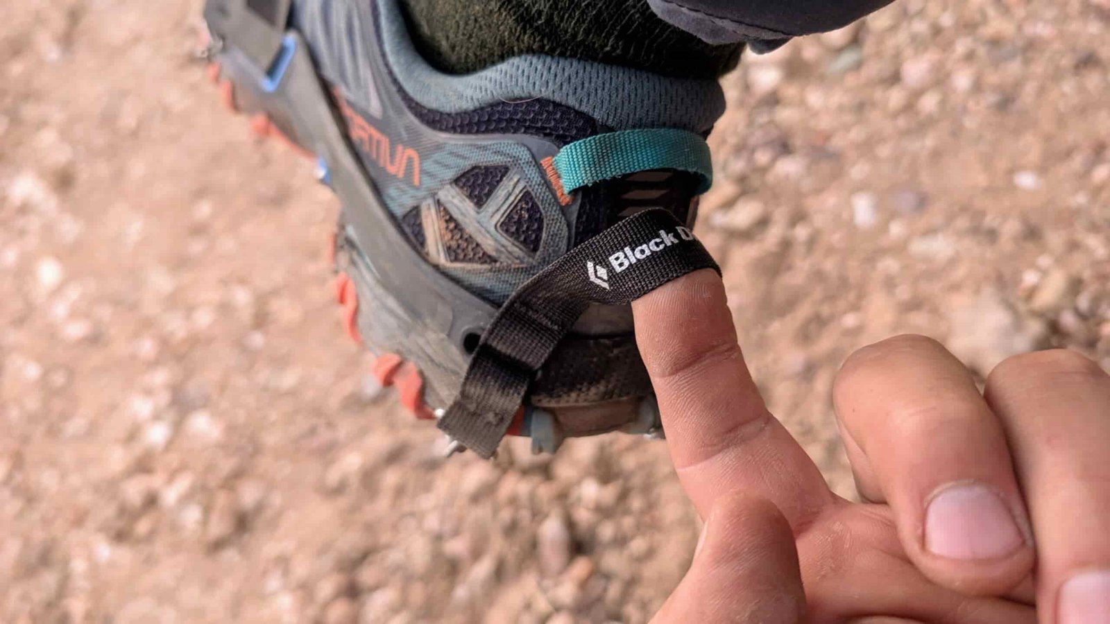 a close up of a finger showing the pull tab on the heel of a pair of ice cleats