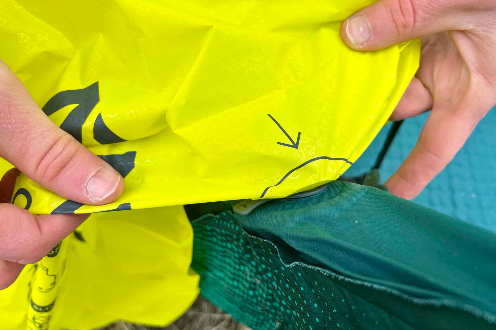 Close-up image of two hands holding a stuff sack attached to the nozzle of a mattress.