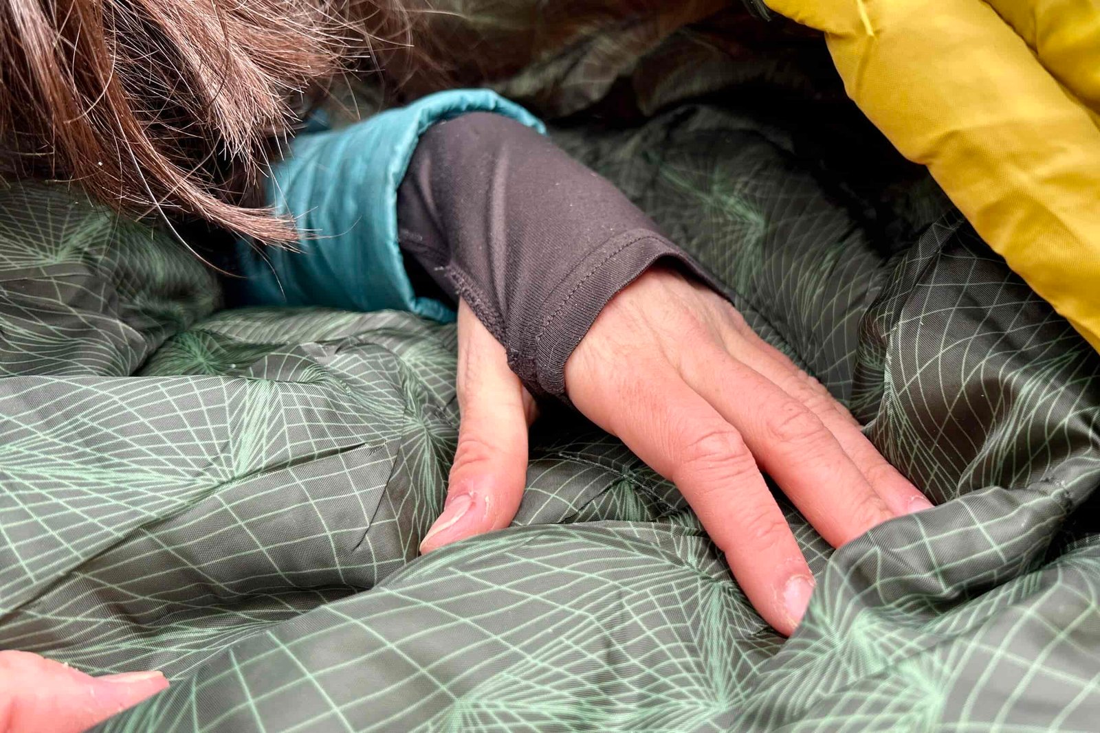A person's hand rests on the interior of a sleeping bag.