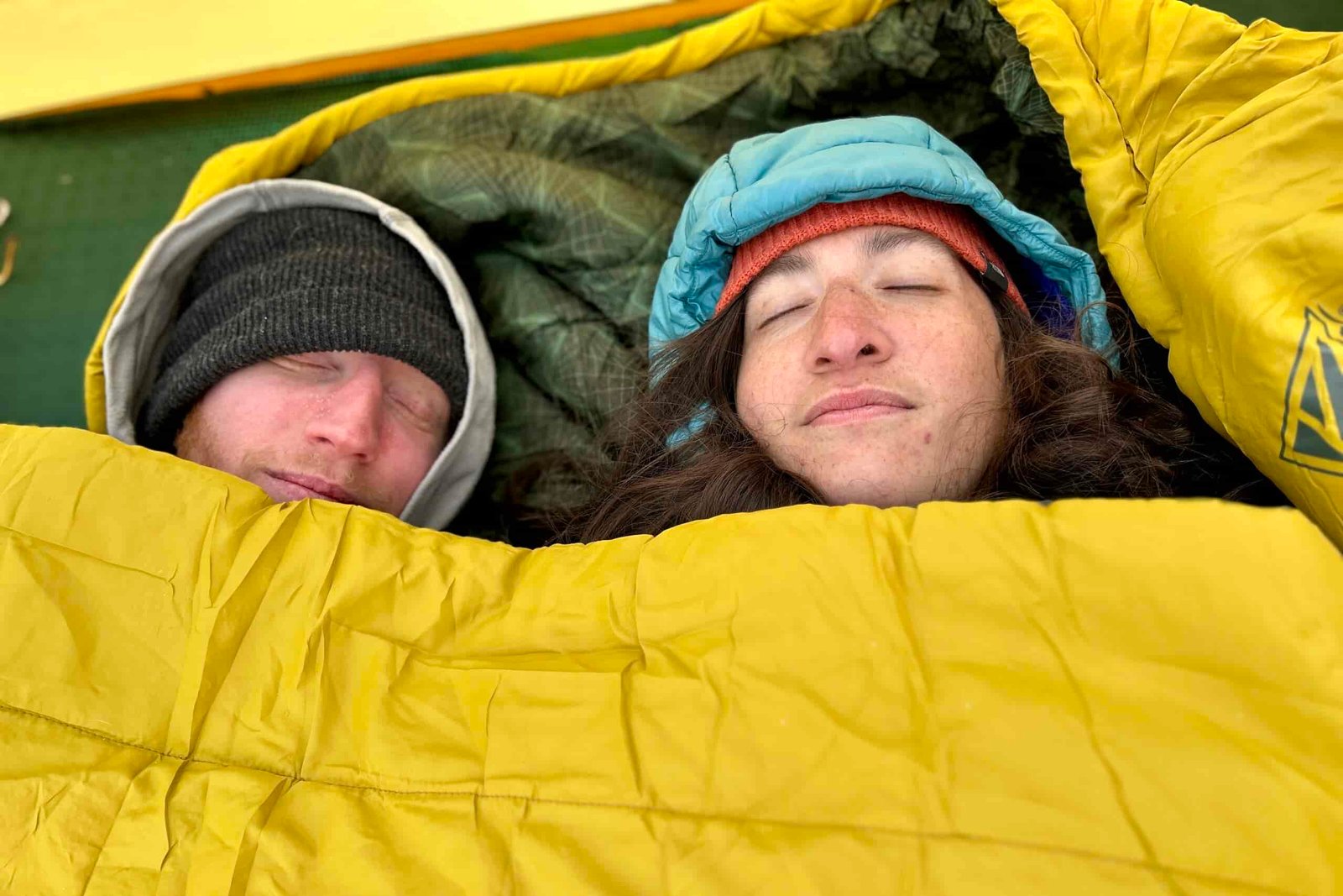 Close-up image of two people from above resting in a double sleeping bag.