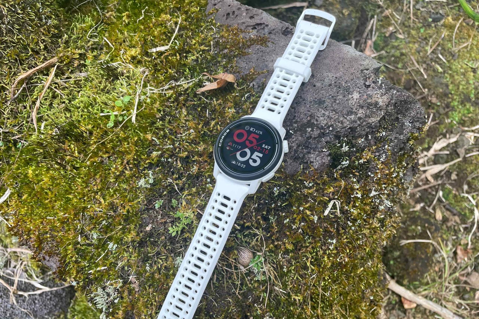 A GPS watch sits on a mossy rock.