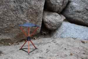 REI stool set up on the stand in front of gray boulders