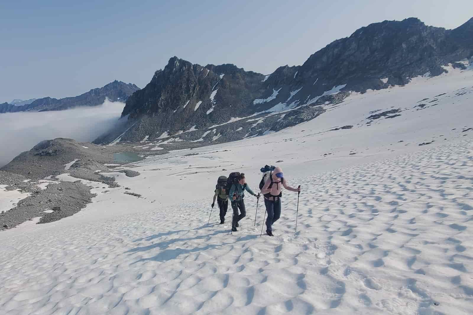 A party of three hikes up a glacier.