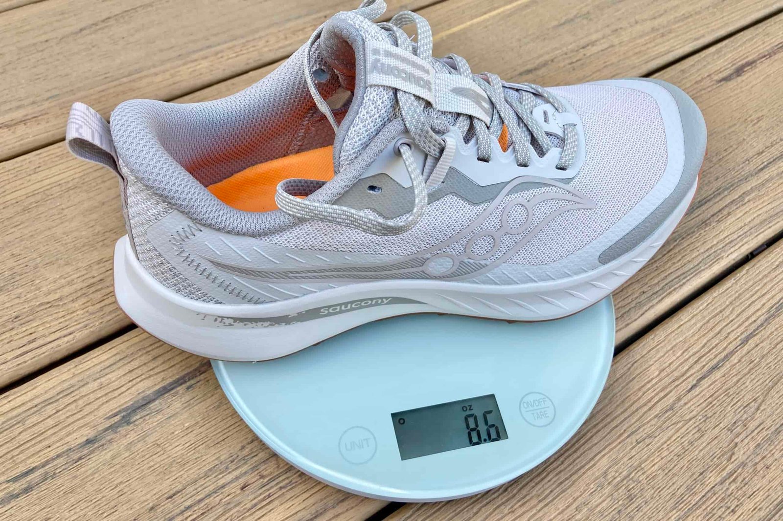 Close-up showing one Saucony shoe sitting on a kitchen scale. It weighs 8.6 ounces in size women’s 8.5.