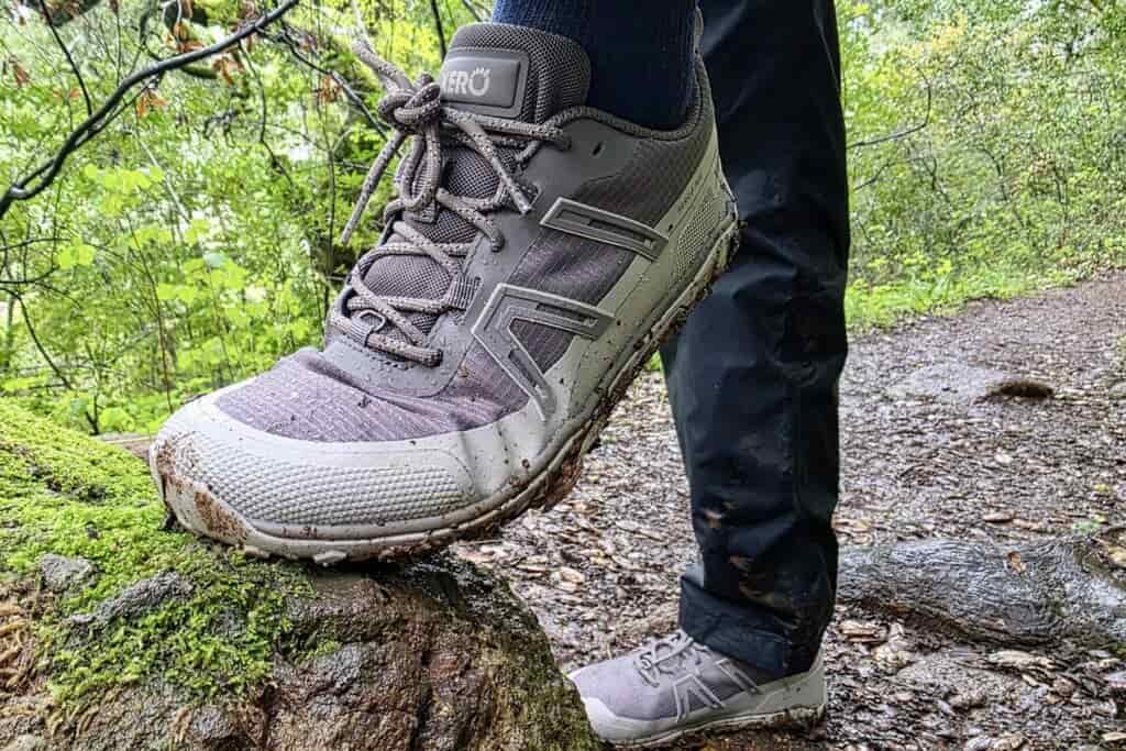 Person stepping up on a rock, showing the creasing of her shoe’s upper material where her foot bends.