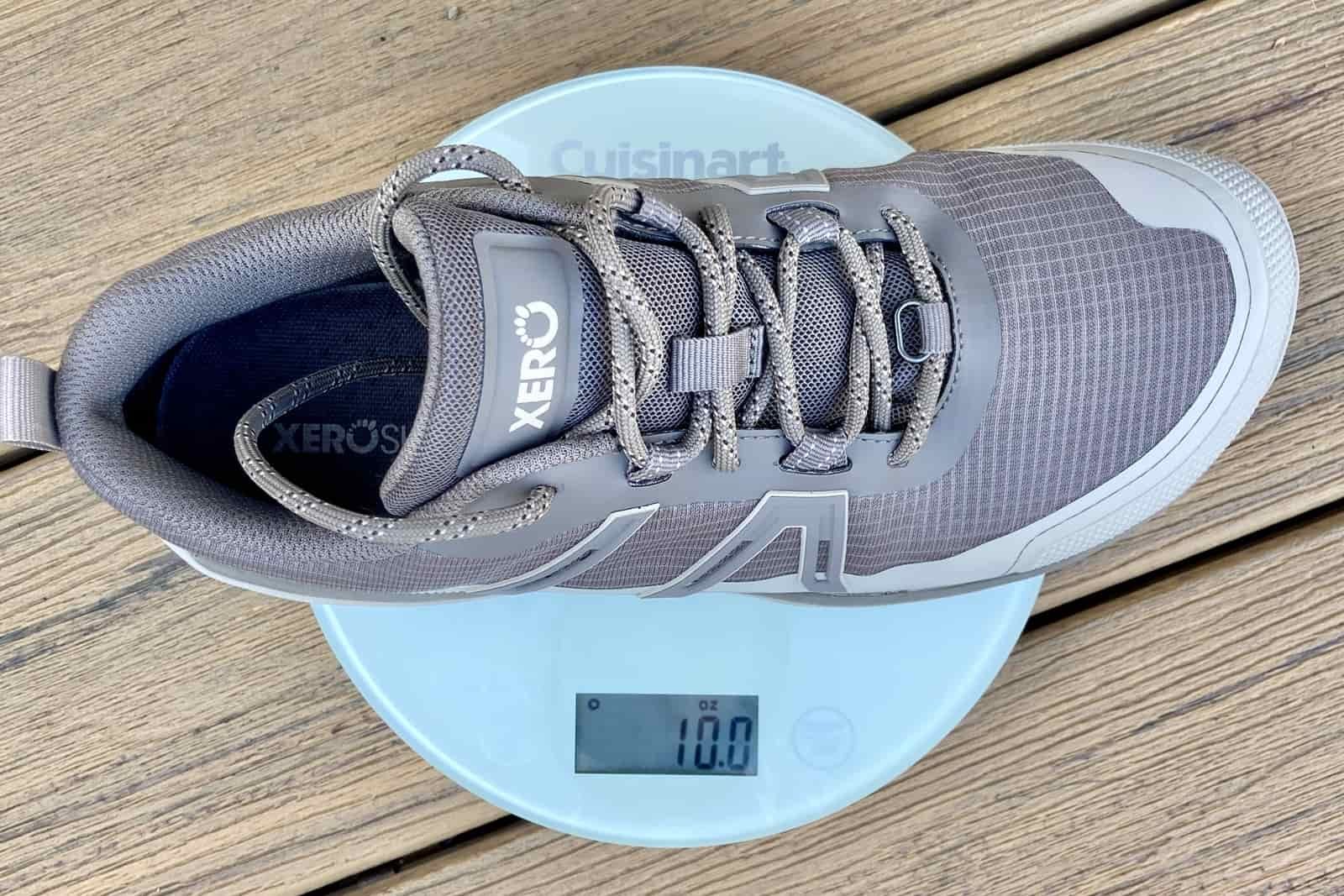Close up showing one hiking shoe on a kitchen scale, which weighs 10 ounces.