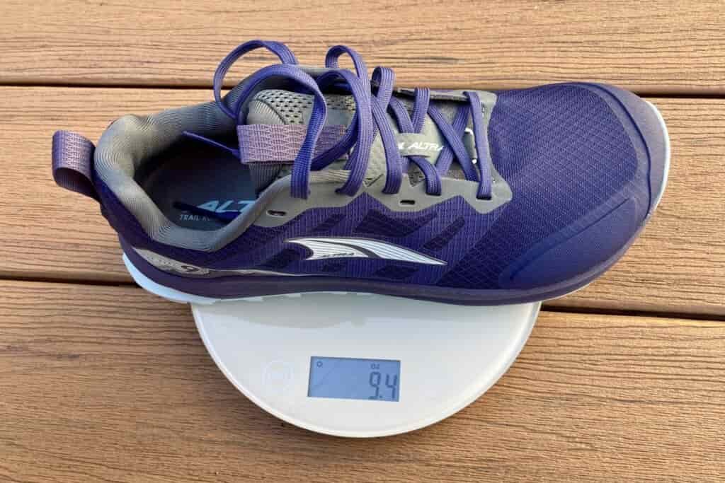 Close up showing one Altra shoe sitting on a kitchen scale. It weighs 9.4 ounces.