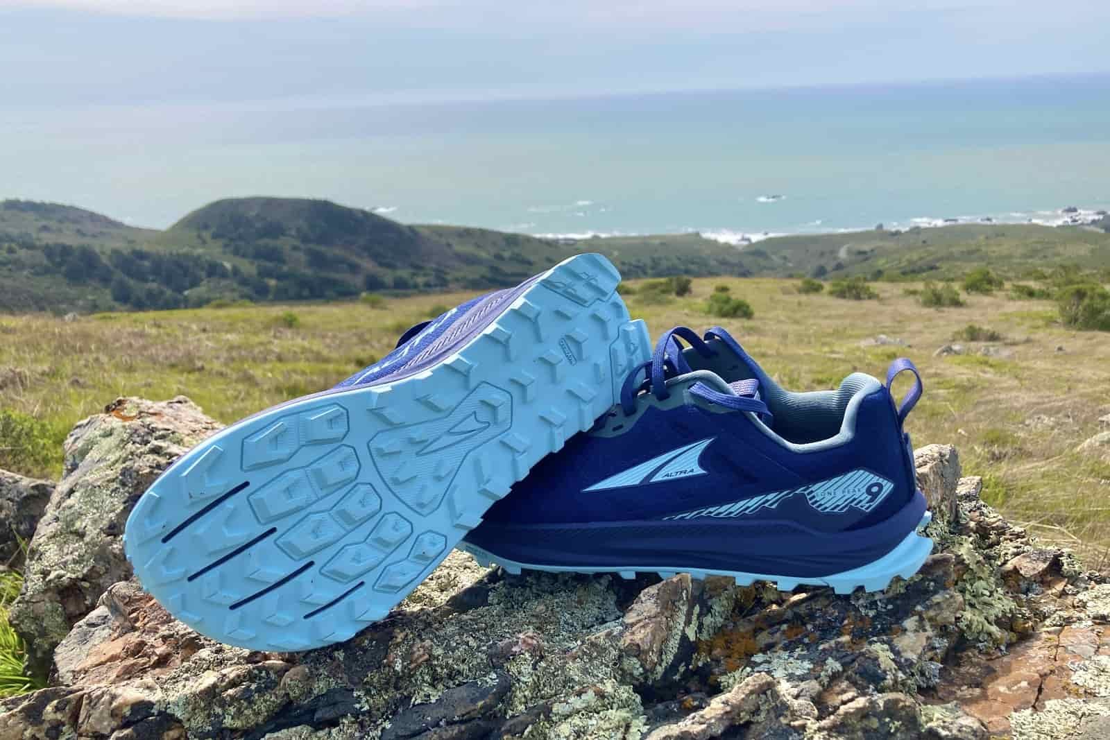 A pair of Altra shoes sits on an overlook over the Pacific Ocean.