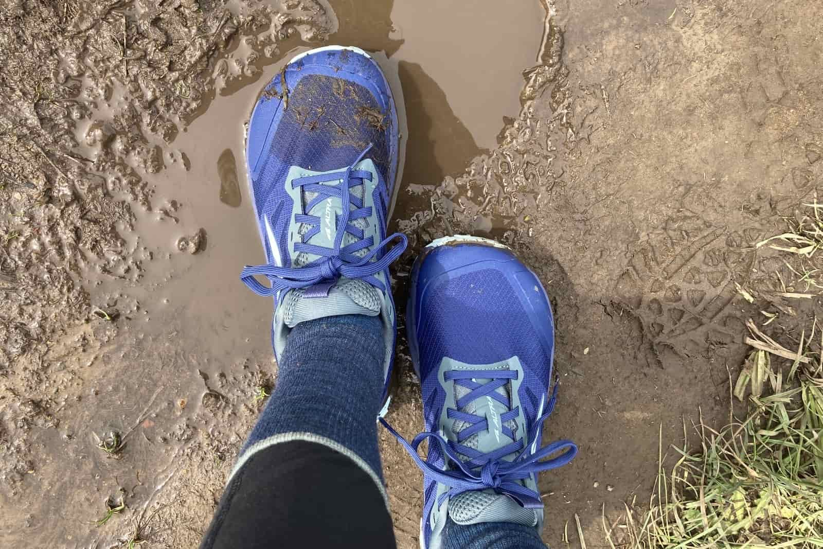 Close up showing the Altra shoes, while standing in a mud puddle