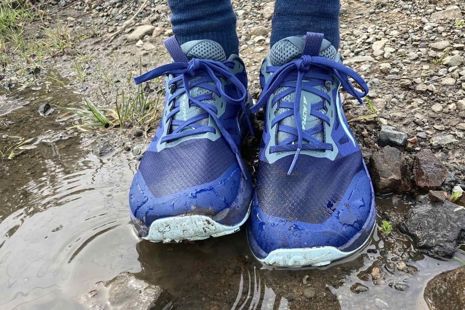 Altra shoes sit in a puddle, coated with water.