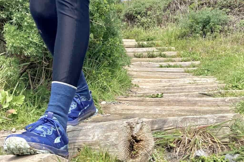 Person hiking down a a trail wearing the Altra Lone Peak 9 shoes