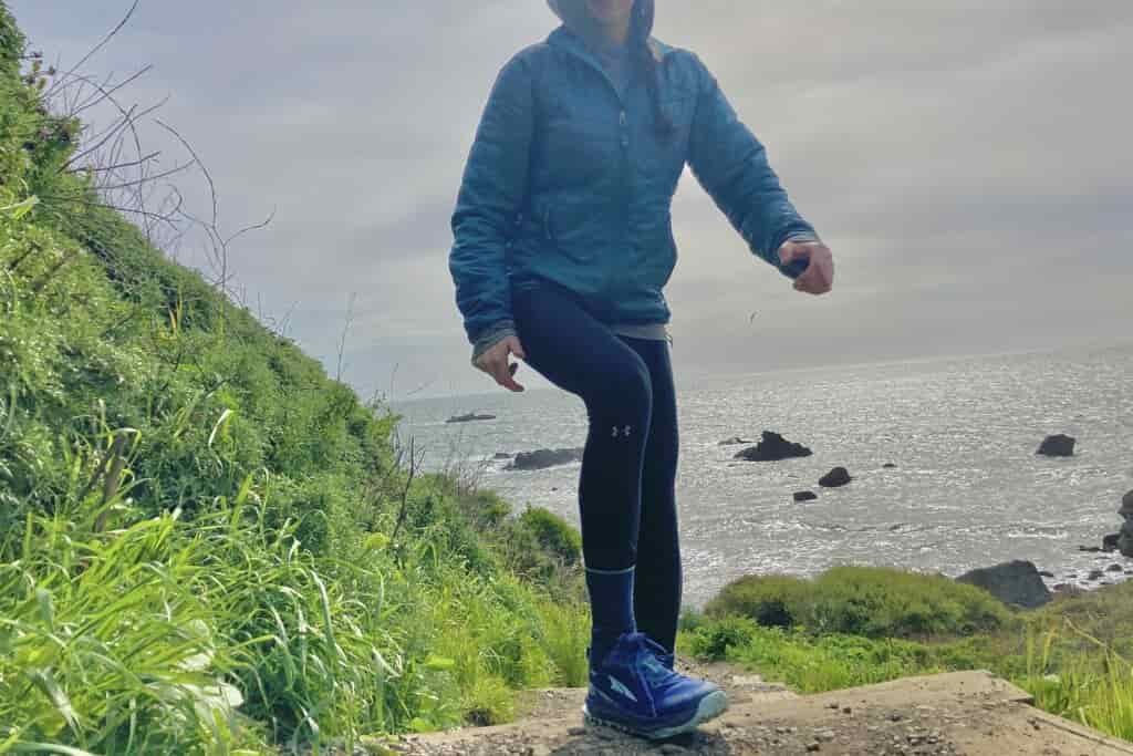 Person hiking up a coastal trail, wearing the newest version of the Lone Peaks.