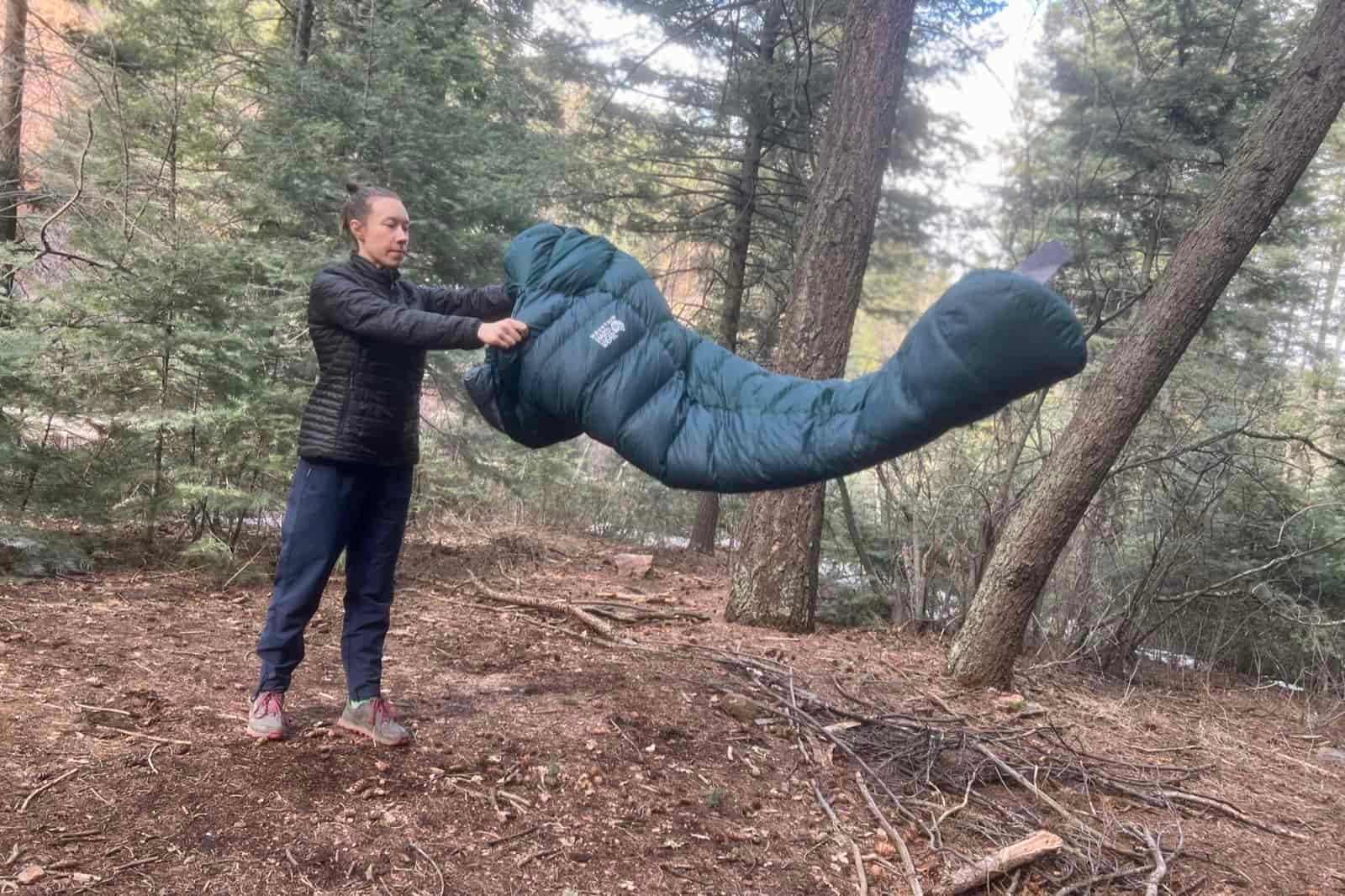 A hiker tosses a sleeping bag in the woods