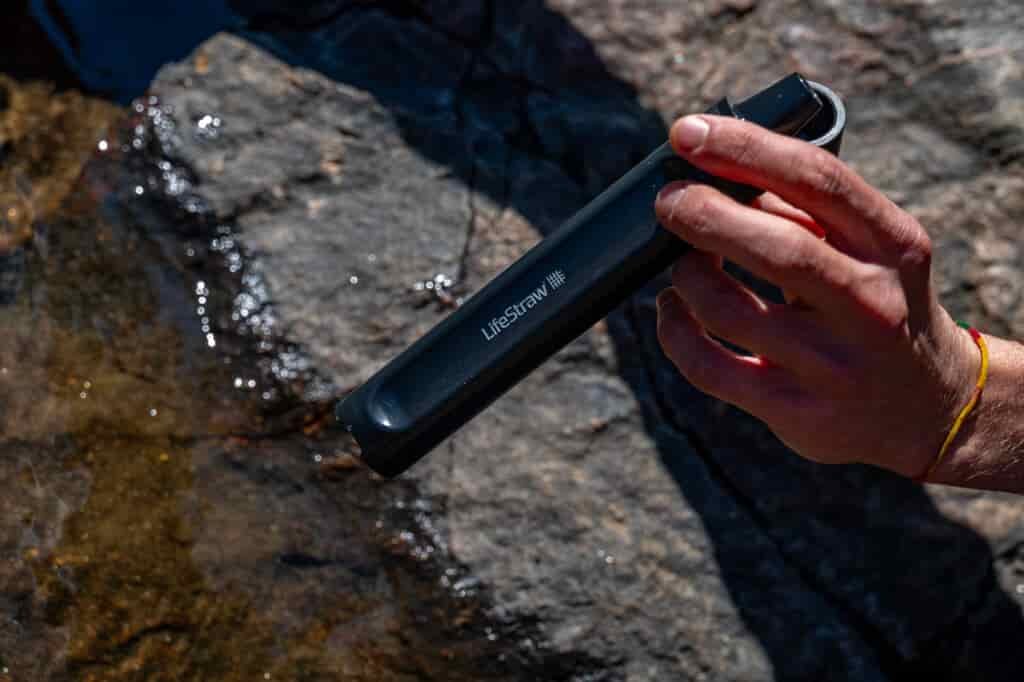 A close up of a hand holding a straw water filter