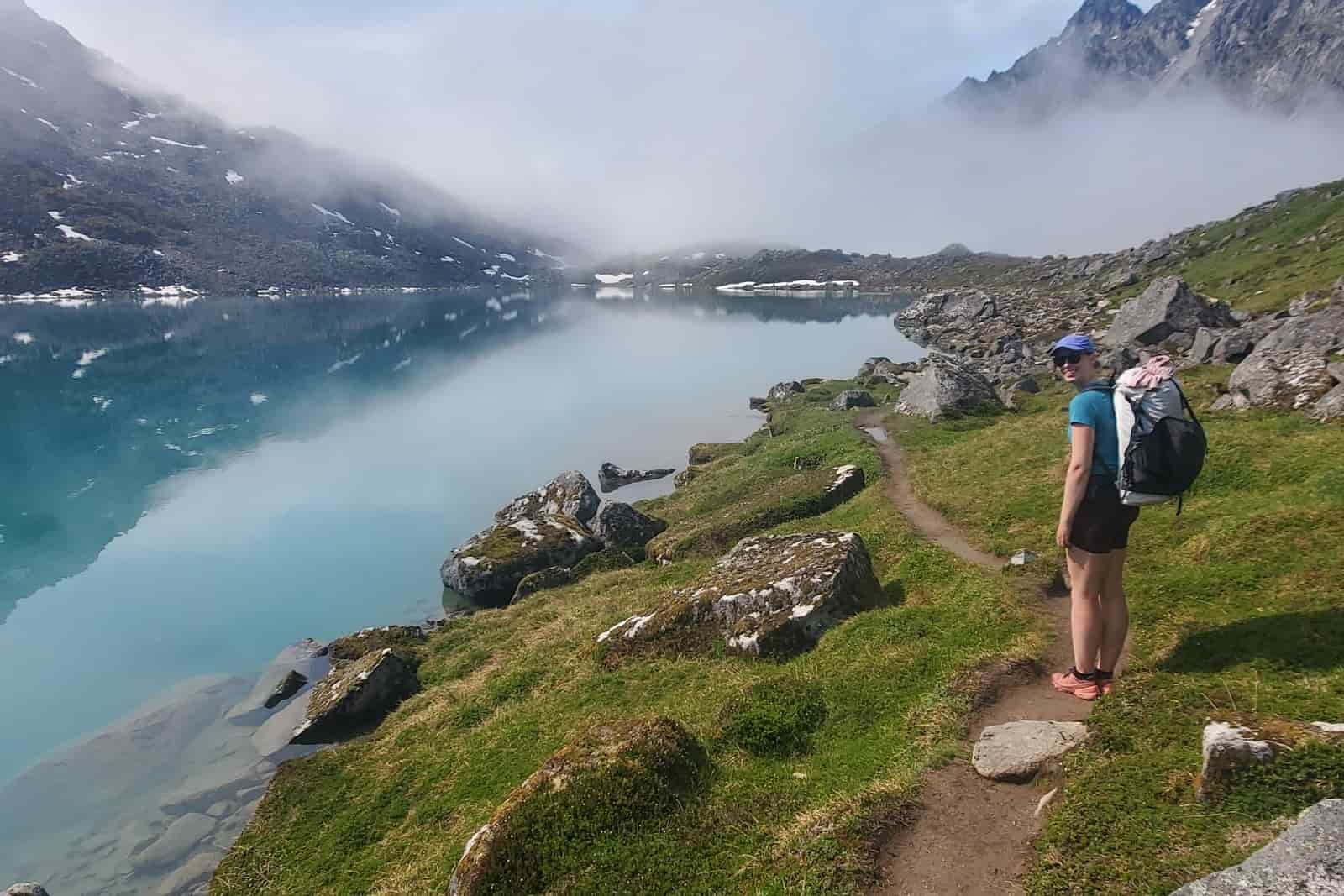 A woman hikes along an alpine lake.