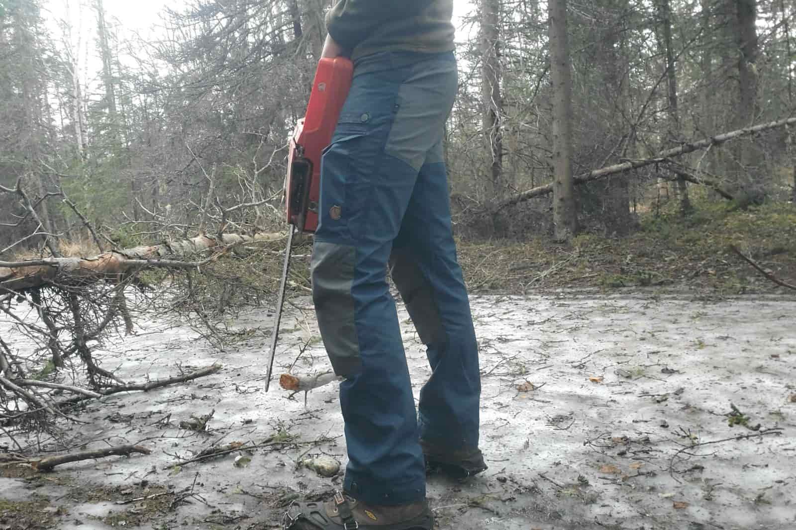 A man works on a trail wearing blue hiking pants.