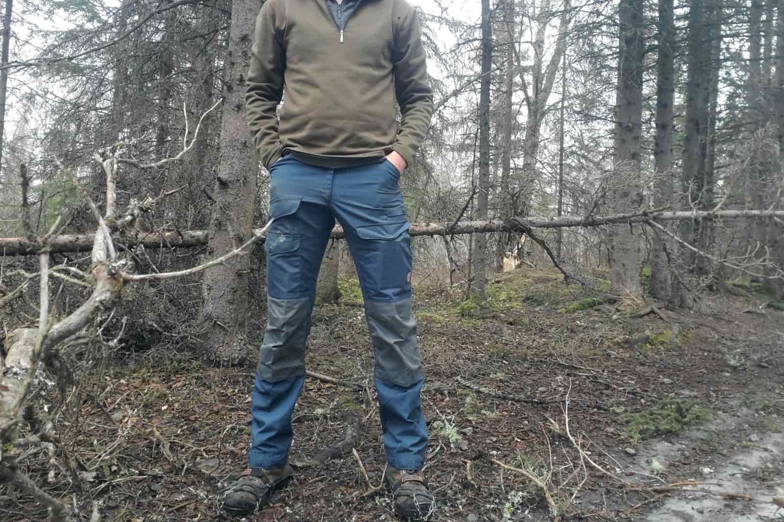 A front shot of a man standing wearing blue pants.