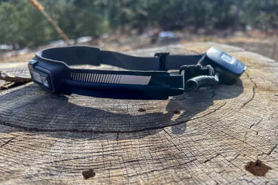 a closeup of a headlamp sitting on a stump in a forest.